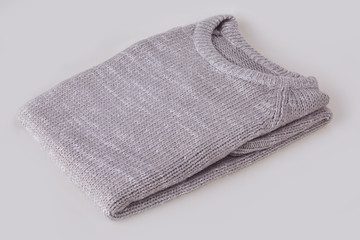 Gray folded knitted sweater with blank tag on white background. Clothes, fashion concept. Long sleeve tunic