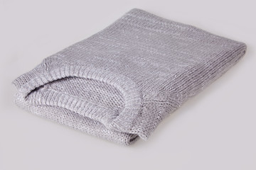 Gray folded knitted sweater with blank tag on white background. Clothes, fashion concept. Long sleeve tunic