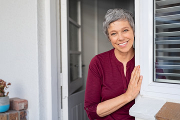 Happy senior woman leaning at door
