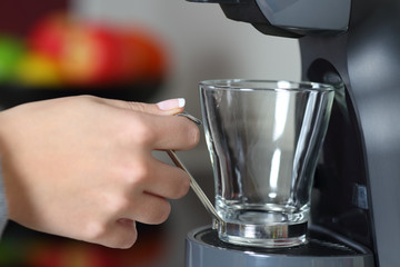 Woman hand holding an empty cup in a coffee maker