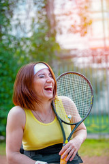 Disabled young woman on wheelchair playing tennis on tennis court.