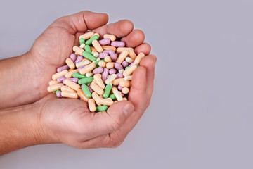 Man's hand holding colorful pills isolated on white background. Vitamin supplements tablets