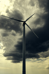The wind generator is in dark stormy sky.