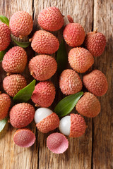 Fresh lychee and peeled showing the red skin and white flesh with green leaf. Vertical top view