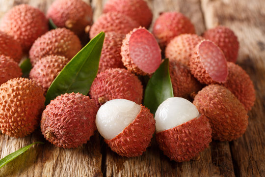 Fresh lychee and peeled showing the red skin and white flesh with green leaf. horizontal