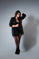 Plus size fashion model in sexy clothes, fat woman on gray studio background, overweight female body