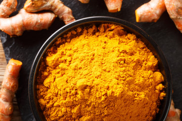 Ground fresh turmeric in a bowl and root close-up. Horizontal top view