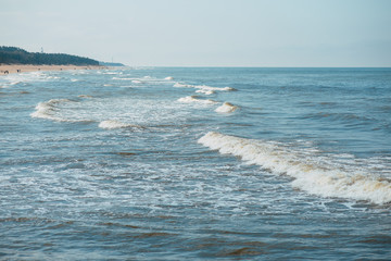 Sandy beach and blue sea with waves and seafoam. Background image for travel, summer vacation, and recreation. Vivid photo of tropical paradise.