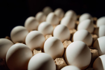 Top view of opened box with eggs on black background. Fresh chicken eggs closeup