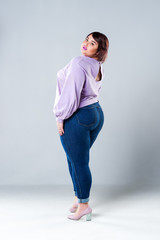 Plus size fashion model in casual clothes, fat woman on gray background