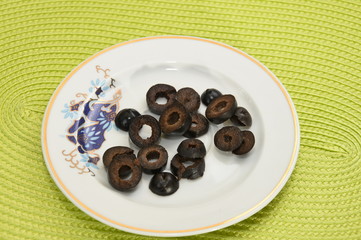 black olives in a glass ashtray on black background
