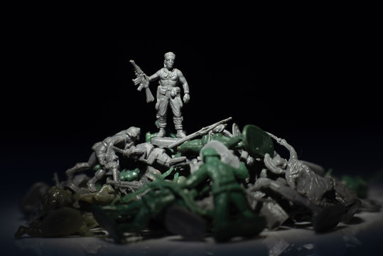 Image one soldier standing over the dead plastic toy soldier against the dark background