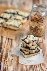 Shortbread cookies with blueberry jam on baking paper on wooden background. 