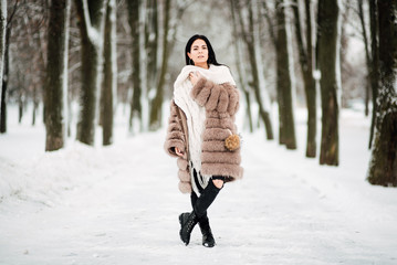 beautiful young girl with black hair in fur coat in winter outdoors, woman alone outside snowy frosty day