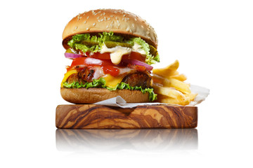 Delicious burger with potato fries on a wooden plank, isolated on white background