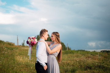 Young cute bride with bouquet of flowers hugging the groom on nature. Beautiful wedding couple outdoor portrait. Portrait of a loving couple. Wedding photo session. Second half. Newlywed
