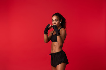 Portrait of young african american woman in black sportswear boxing with sports bandages on her...