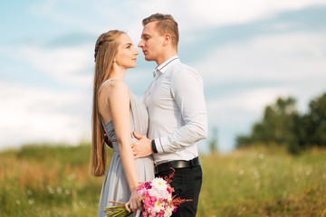 Young cute bride with bouquet of flowers hugging the groom on nature. Beautiful wedding couple outdoor portrait. Portrait of a loving couple. Wedding photo session. Second half. Newlywed
