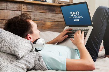 Man doing SEO keyword positioning with a laptop at home.