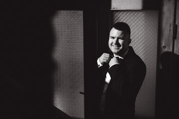 Black and white photo of man who look at the light from the window. Fashion man in suit