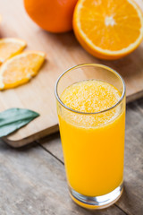Glass of orange juice and fresh fruits on wooden background