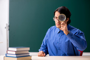 Young male teacher in front of chalkboard  