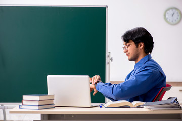 Young male teacher in front of chalkboard  