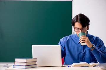 Young male teacher in front of chalkboard  