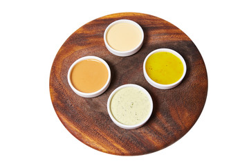 Different sauces (ginger, spinach, mayonnaise, mustard, tomato) on a wooden plate (board) isolated on white background