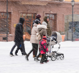 Family walk with the child in the stroller in snowy winter day