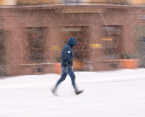 Woman walking down the street in winter snowy day in motion blur