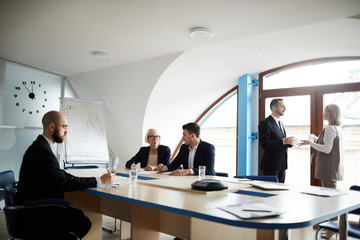 Several colleagues in formalwear discussing working moments in boardroom or conference hall