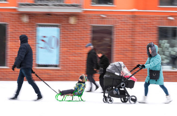 Family walk with the child in the stroller in snowy winetr day