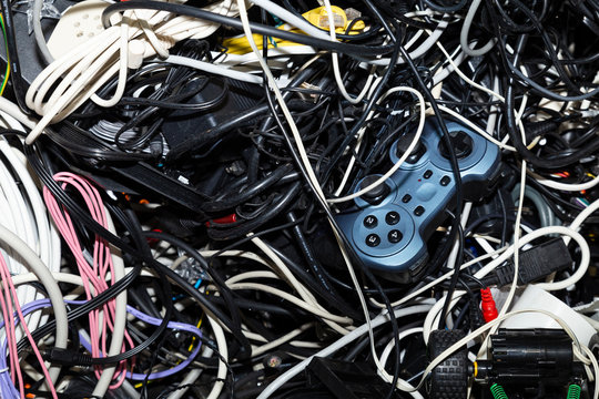 Close-up of an entangled heap of electronic scrap including a game console controller waiting for recycling