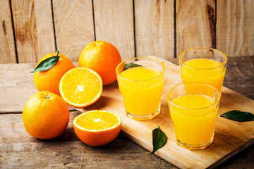 Orange juice. Glasses of orange juice and fruits against wooden background