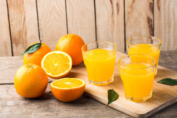 Orange juice. Glasses of orange juice and fruits against wooden background
