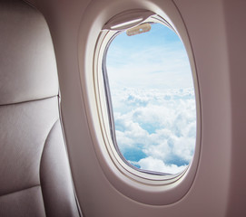 Airplane interior with window view of clouds.