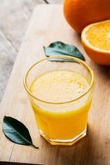 Fresh orange juice and oranges on wooden table