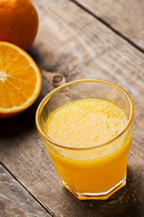 Fresh orange juice and oranges on wooden table
