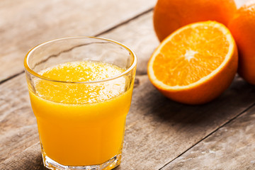 Fresh orange juice and oranges on wooden table
