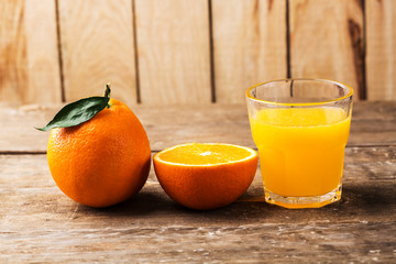 Fresh orange juice and oranges on wooden table