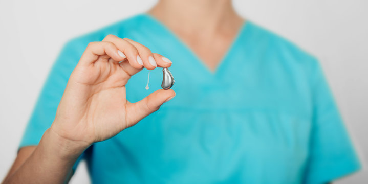 Close-up of a doctors hand holding modern hearing aid. hearing aids-deafness treatment
