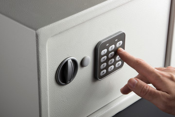 Fototapeta the hand opens a combination lock on the safe, a light safe on a dark background obraz