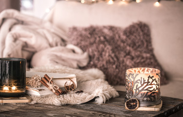 still life home atmosphere in the interior with candles and a book on the background of cozy...