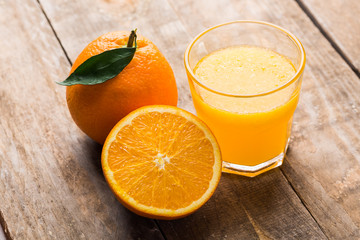 Glass of orange juice and fruits on wooden background