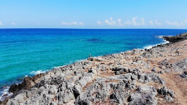 Aerial fly over rocky beach, stone pyramids and blue sea, Crete, Greece