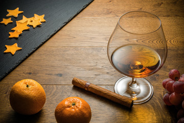 Glass of cognac and cigar with snack on the wood table with stone cutting board. Top view with copy...