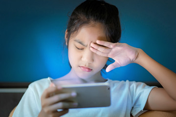 teenage girl  hurt her eyes because she played the smart phone in the dark light  and the blue light has a negative effect on the child's eyes.