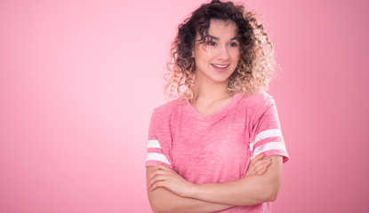 Fototapeta premium Portrait of a beautiful cheerful girl with curly hair on a pink background