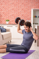 Fototapeta na wymiar Young handsome man doing sport exercises at home 
